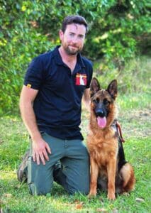 K9 trainer with German Shepherd dog outdoors, showcasing obedience training and companionship skills.